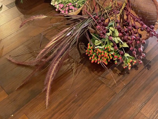 紫がかった穂ものとオレンジの実をクローズアップした写真。かごの中の植物材料